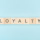 top view of loyalty lettering made of wooden cubes on blue backg