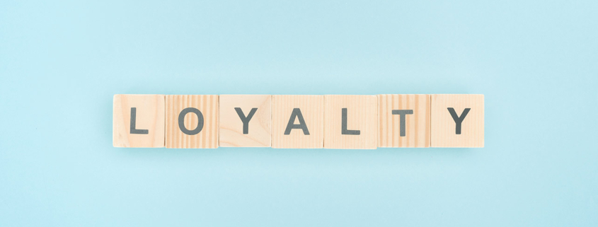 top view of loyalty lettering made of wooden cubes on blue backg